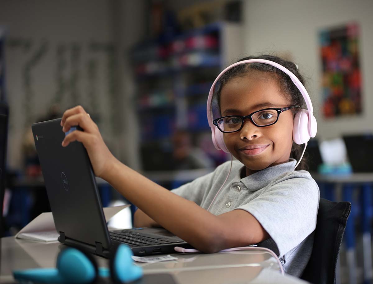 Elementary student smiling and posing together in a classroom.